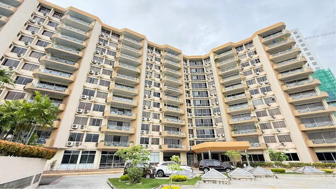 Multistory residential building with balconies and cars parked in front