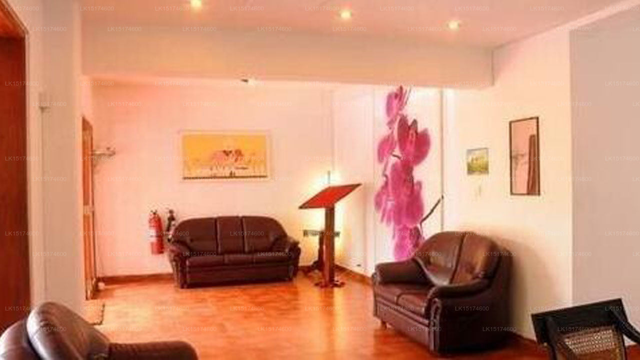 Living room with brown leather sofas, a pink flower arrangement, and framed pictures on white walls.