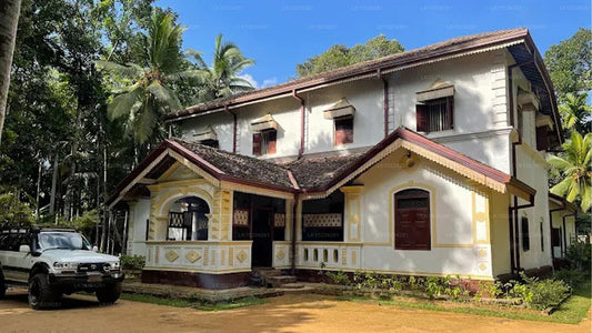Traditional house with a car parked in front, surrounded by trees