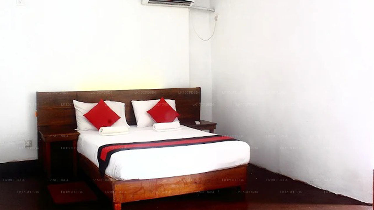 Bedroom with a bed featuring red pillows and a white comforter, wooden headboard, and air conditioner on the wall.