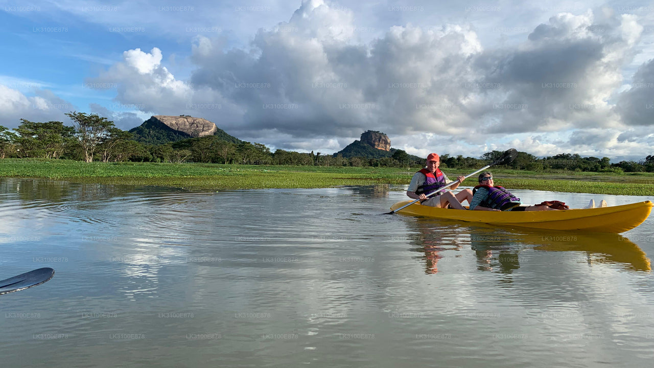 Two people in a yellow kayak on a calm body of water with a scenic background.
