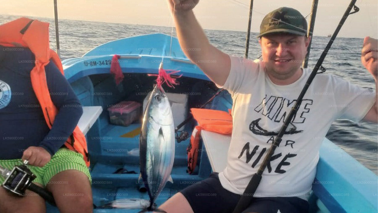 Person on a boat holding a fish with another person in the background.