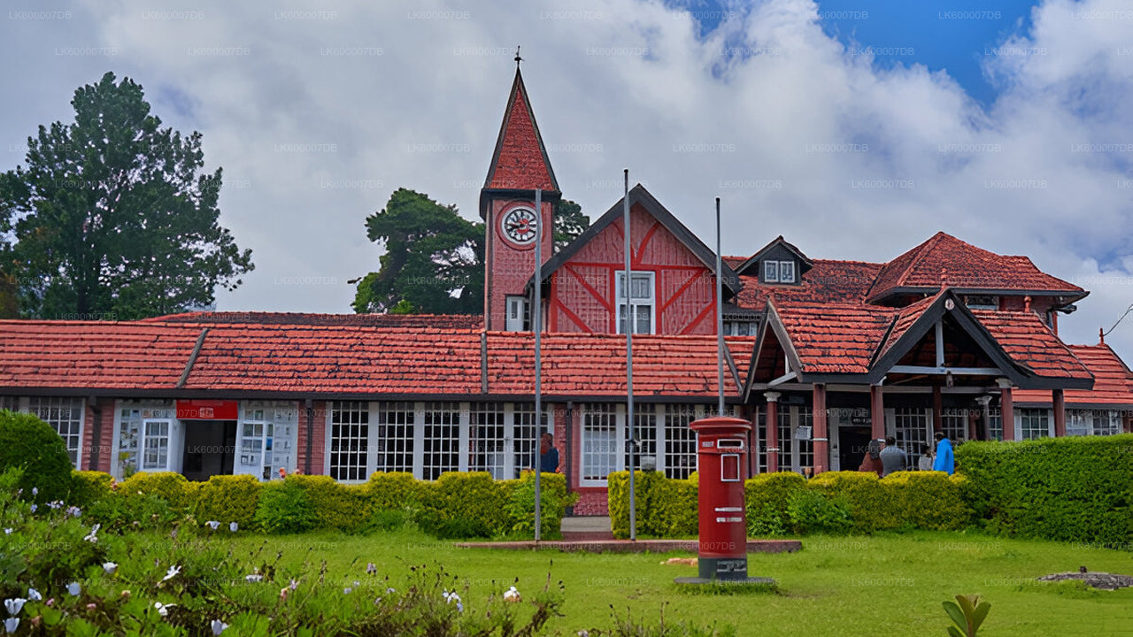 Red brick building with a clock tower in a lush green garden